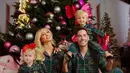 Paris Hilton bersama suami dan kedua anaknya berfoto di depan pohon Natal dengan hiasan kupu-kupu. Keluarga ini pun tampil dengan piyama hijau motif kotak-kotak. [@parishilton]