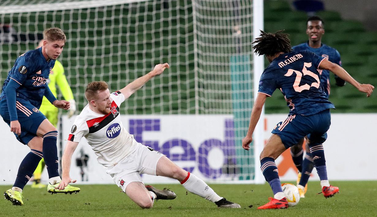 Gelandang Arsenal, Mohamed Elneny, berebut bola dengan bek Dundalk, Andy Boyle, pada laga lanjutan Liga Europa 2020/2021 di Aviva Stadium, Jumat (11/12/2020) dini hari WIB. Arsenal menang 4-2 atas Dundalk. (AFP/Paul Faith)