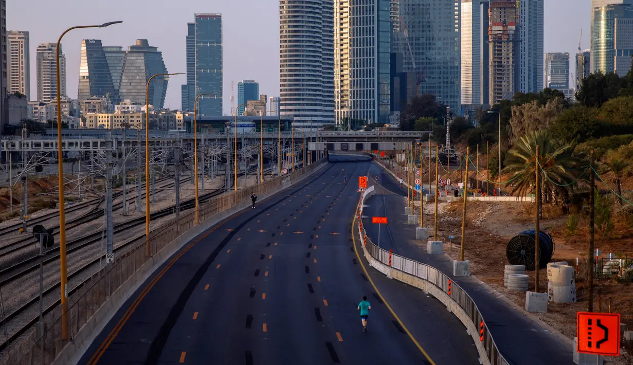 Seorang pria berlari di jalan raya bebas mobil selama hari libur Yahudi Yom Kippur, di Tel Aviv, Israel, Senin(28/9/2020). Liburan khusyuk yang setiap tahun melihat kehidupan dan keramaian di Israel akan terhenti, kali ini berlangsung di tengah lockdown selama tiga minggu. (AP Photo/Oded Balilty)