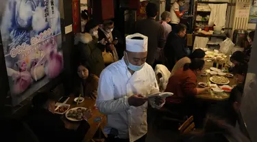 Seorang pekerja bersiap untuk melayani pelanggan di sebuah restoran yang terkenal dengan pangsitnya selama hari titik balik matahari musim dingin di Beijing, China, Selasa (21/12/2021). Pangsit adalah makanan festival selama hari titik balik matahari musim dingin. (AP Photo/Ng Han Guan)