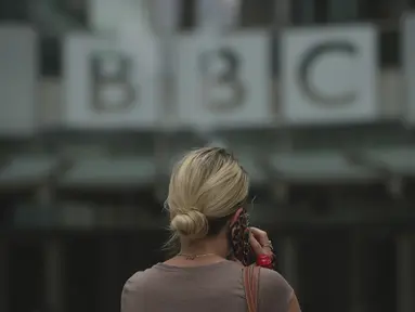 Seorang perempuan berjalan di luar Markas Besar BBC di London, Inggris, Selasa (11/7/2023). Detektif Inggris bertemu dengan perwakilan BBC pada hari Senin atas tuduhan bahwa seorang presenter terkemuka membayar seorang remaja untuk foto-foto eksplisit secara seksual. (AP Photo/Kin Cheung)