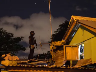 Seorang polisi terus berjaga dari atap selama penggerebekan bandar narkoba di Desa Maharlika, Taguig, selatan Manila (28/2). Penggerebekan dilakukan untuk menangkap lima pengedar narkoba, namun hanya dua yang ditangkap. (AFP Photo/Noel Celis)