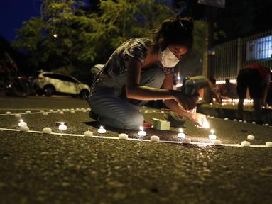 Belen Nunez menyalakan lilin untuk mengenang mereka yang meninggal akibat virus corona di depan Kementerian Kesehatan di Asuncion, Paraguay, Minggu (14/3/2021). Sejuah ini, Paraguay mencatat 3.450 kasus kematian akibat COVID-19. (AP Photo/Jorge Saenz)