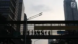 Pejalan kaki melintas di JPO Jalan Sudirman yang dipasangkan Spanduk peringatan revitalisasi, Jakarta (6/11). Ketiga JPO yang akan direvitalisasi mendapatkan penambahan lift dan CCTV. (Liputan6.com/Immanuel Antonius)