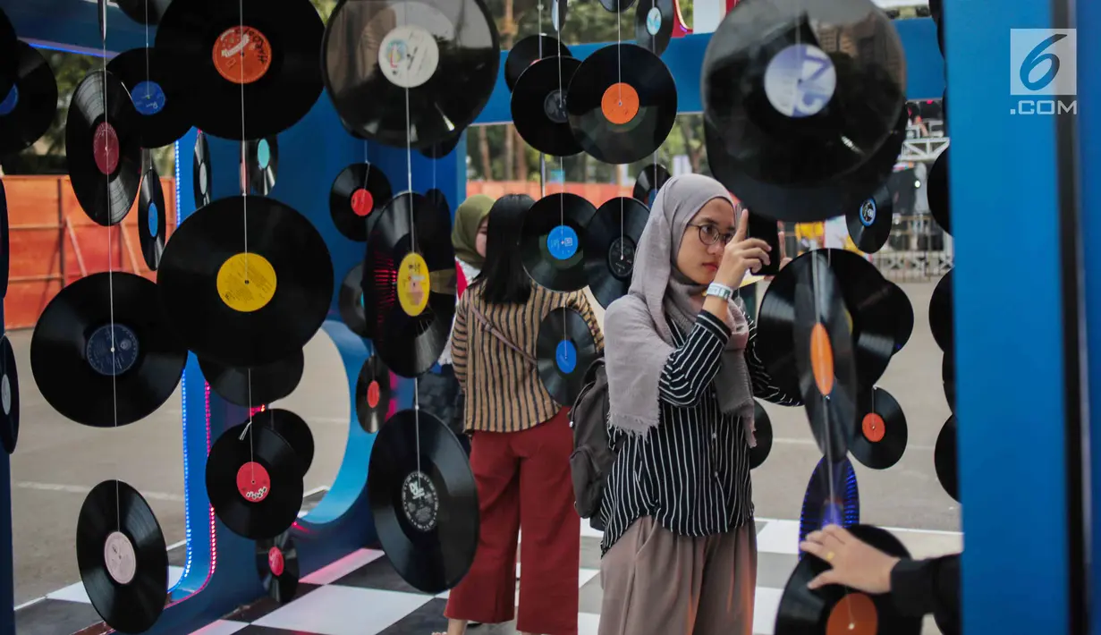 Pengunjung melihat-lihat laserdisc yang ada dalam acara Playfest 2019 di Parkir Selatan Gelora Bung Karno, Jakarta, Minggu (25/8/2019). Playfest 2019 mengusung konsep retro 90-an. (Liputan6.com/Faizal Fanani)