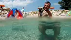 Seorang pria berenang bersama anjingnya di pantai anjing dan bar di Crikvenica, Kroasia, (12/7). Pantai dan bar ini dirancang khusus untuk para anjing dan pemiliknya demi merasakan kenikmatan Summertime bersama-sama. (REUTERS/Antonio Bronic)