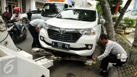 Petugas Dishub DKI memasang alat derek pada mobil yang parkir liar di kawasan Pasar Baru, Jakarta, Senin (27/6). Penertiban rutin ini dilakukan untuk membuat efek jera bagi warga yang masih parkir sembarangan. (Liputan6.com/Gempur M Surya)