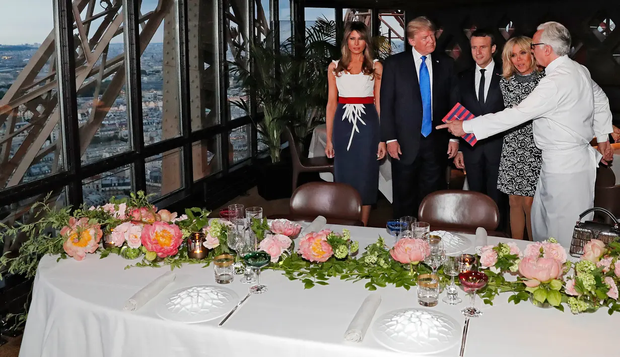 Koki Prancis Alain Ducasse mempersilahkan Presiden AS Donald Trump dan Melania Trump serta Presiden Prancis Emmanuel Macron dan istrinya, Brigitte Macron untuk jamuan makan malam di Menara Eifel, Paris, Kamis (13/7). (Yves Herman/Pool Photo via AP)