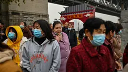 Turis domestik dari provinsi Henan yang mengenakan masker wajah mengunjungi daerah di sebelah Sungai Yangtze di Wuhan (20/11/2020). Dari total 50.340 kasus yang positif di Wuhan, 3.869 orang telah meninggal dunia akibat Covid-19 dan yang sembuh 46.471 orang. (AFP/Hector Retamal)