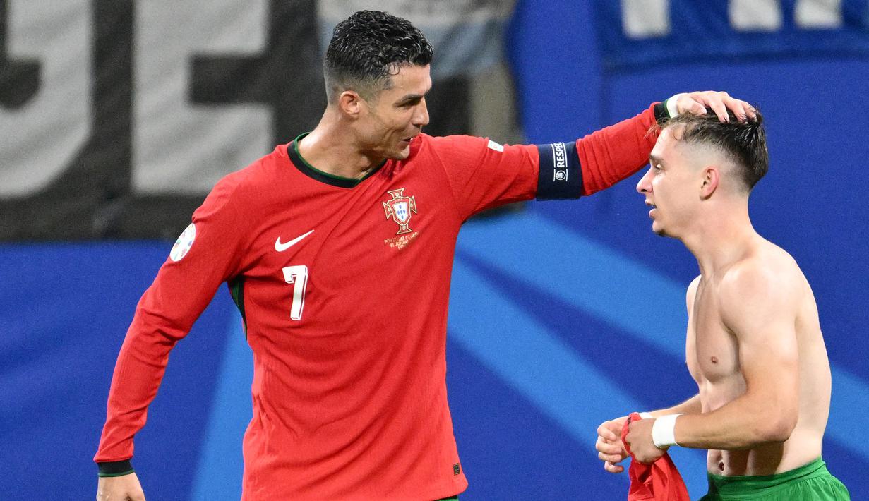 Penyerang Portugal #07 Cristiano Ronaldo mengucapkan selamat kepada #26 Francisco Conceicao setelah ia mencetak gol kedua timnya ke gawang Republik Ceko pada laga grup F Euro 2024 di Red Bull Arena, Leipzig, Rabu (19/6/2024) dini hari WIB. (Christophe SIMON / AFP)