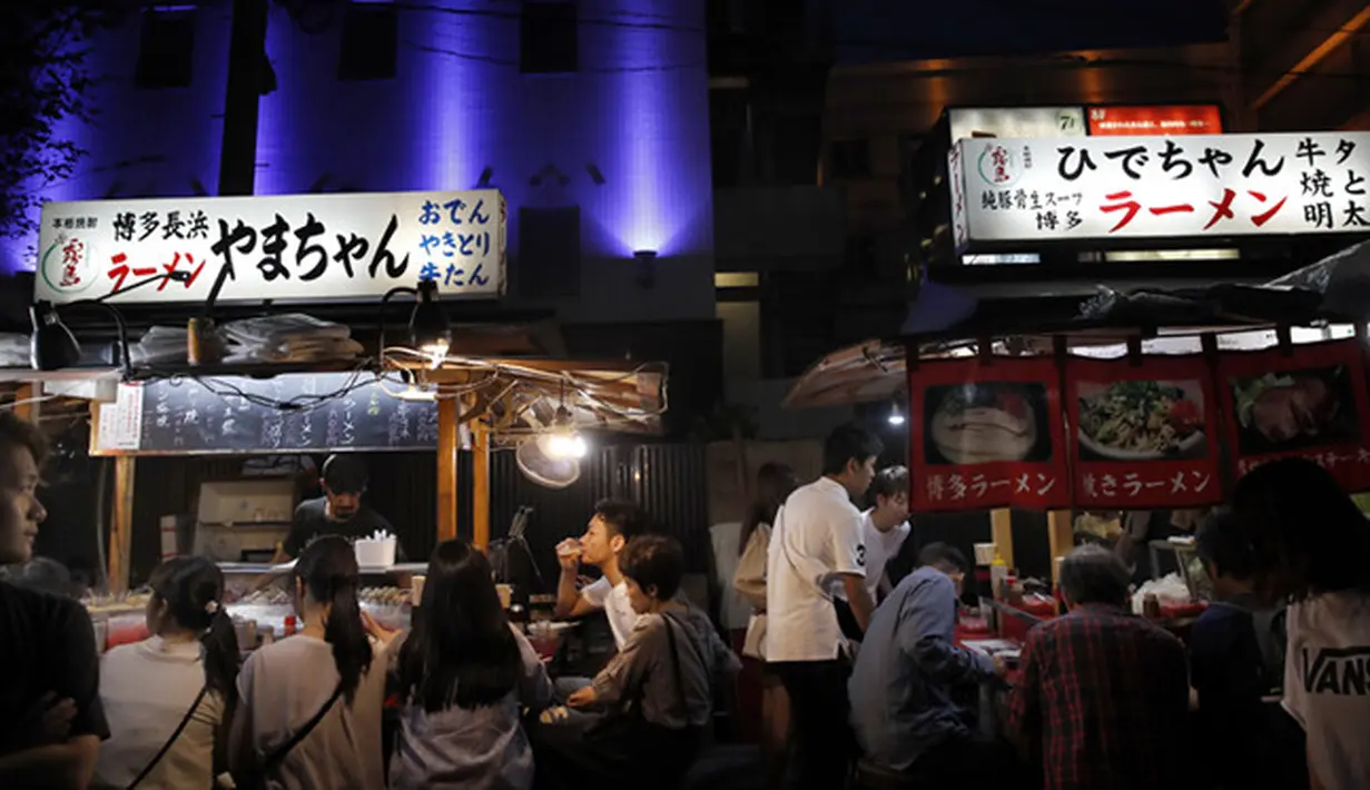 Orang-orang menikmati makan malam di stand makanan terbuka (Yatai) di Fukuoka, Jepang barat daya (30/9/2019). Yatai menyediakan lingkungan luar ruangan yang nyaman untuk menikmati berbagai makanan yang umumnya sederhana dan mengenyangkan. (AP Photo/Christophe Ena)