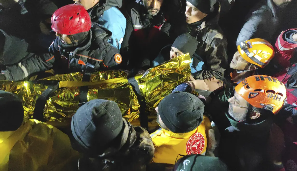 Petugas penyelamat dan petugas medis membawa seorang wanita muda yang telah mereka selamatkan dari puing-puing bangunan yang runtuh di Sanliurfa, Turki selatan, Senin malam, 6 Februari 2023. Tim penyelamat di Turki dan Suriah mencari sepanjang malam yang dingin hingga Selasa, berharap untuk menarik lebih banyak orang yang selamat dari puing-puing setelah gempa bumi yang kuat. (IHA via AP)