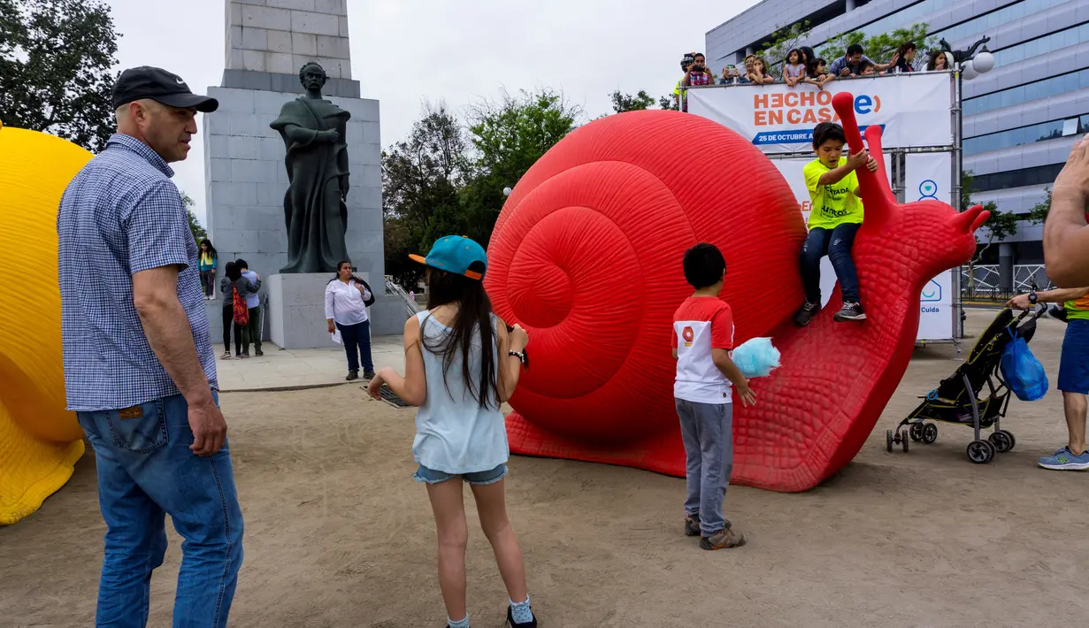 Anak-anak bermain dengan siput raksasa, bagian dari seni instalasi "Hecho en Casa" yang menghiasi pedestrian kota Santiago, Chile, Senin (29/10). Siput raksasa dari plastik daur ulang itu dibuat oleh Cracking Art Group asal Italia. (Martin BERNETTI/AFP)