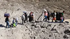 Orang-orang yang melarikan diri dari pengeboman Israel di Lebanon, berjalan di sekitar area lubang yang disebabkan oleh serangan Israel, di daerah Masnaa di sisi perbatasan Lebanon dengan Suriah, pada 4 Oktober 2024. (HASSAN JARRAH/AFP)