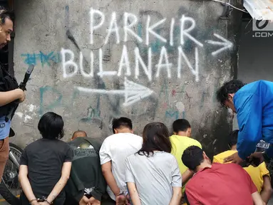 Petugas Polres Jakarta Barat mengamankan terduga pelaku saat penggerebekan di Kampung Boncos, Kota Bambu Selatan, Palmerah Jakarta Barat, Rabu (7/2). Polisi menggerebek dua rumah yang diduga sarang peredaraan narkoba. (Liputan6.com/ Ady Anugrahadi)