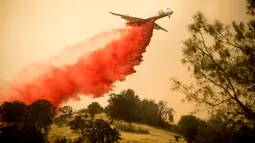 Pemadam kebakaran menggunakan pesawat membuang fire retardant untuk mengatasi kebakaran di Mariposa, California (19/7). Kebakaran ini telah melahap lebih dari 45.000 hektar lahan. (AFP Photo/Josh Edelson)
