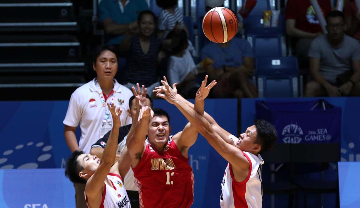 Pebasket putra Indonesia, Ebrahim Lopez Enguio, berusaha melewati hadangan pemain Singapura dalam semi final basket SEA Games 2015. (Bola.com/Arief Bagus)