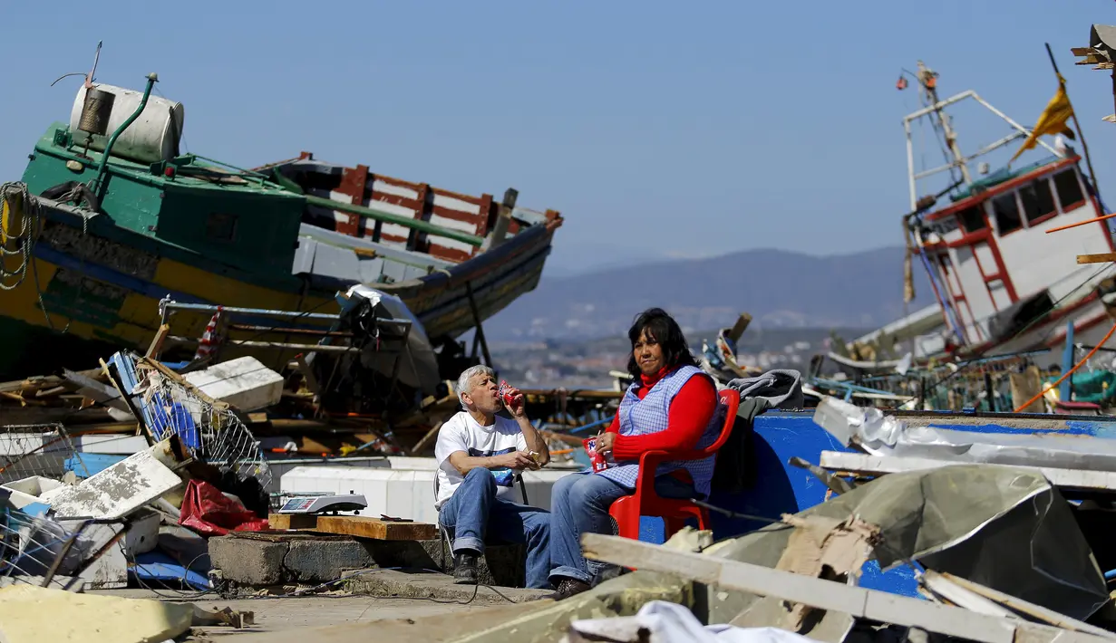 Warga duduk di samping puing-puing dari toko mereka usai gempa bumi melanda Kota Coquimbo, Chile (17/9/2015). Gempa yang menewaskan sekitar sepuluh orang dan memaksa satu juta orang mengungsi dari rumah mereka ke dekat pantai. (REUTERS/Ivan Alvarado)