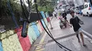 Pejalan kaki melintasi trotoar yang terhalang instalasi kabel di Jalan Kyai Maja, Jakarta, Rabu (10/4). Selain menganggu kenyamanan pejalan kaki, kondisi instalasi kabel yang semrawut tersebut juga berbahaya apabila mengandung aliran listrik. (Liputan6.com/Immanuel Antonius)