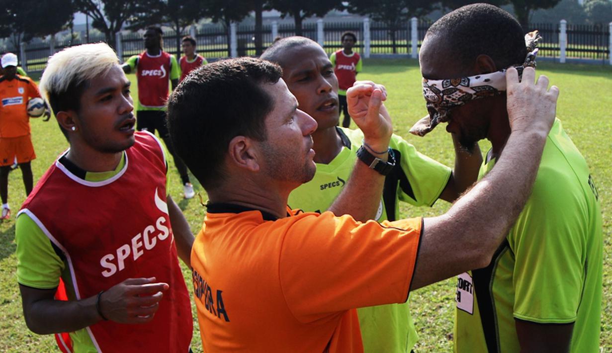 Pelatih Persipura, Osvaldo Lessa, memasang penutup ke mata Lancine Kone saat bermain game mencetak gol ke gawang sambil mata ditutup. (bola.com/Arief Bagus)