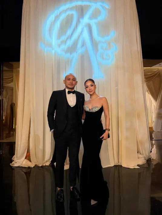 BCL tampil memikat dalam black gown strapless dengan aksen kristal di bagian bustier yang memberi efek glam dan sophisticated. Rambut disanggul rapi, menonjolkan garis leher dan bahu. Tiko tampil maskulin dengan tuxedo hitam dan bow tie, menghadirkan aura formal klasik yang berpadu sempurna dengan gaya glam BCL. [@itsmebcl].