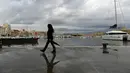 Seorang wanita berjalan dengan payungnya di Vieux-Port di Marseille, Prancis selatan,  Senin (4/10/2021). Wilayah Prancis selatan dalam siaga untuk hujan lebat dan banjir. (AFP Photo/Nicolas Tucat)