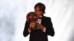 Gelandang Real Madrid, Luka Modric mencium trofi setelah memenangkan penghargaan Ballon d'Or 2018 pada malam penganugerahan di Paris, Senin (3/12). Penghargaan individu ini menjadi gelar Ballon d'Or pertama sepanjang karier Modric. (FRANCK FIFE/AFP)