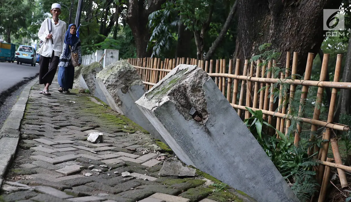 Warga melintas di samping pagar yang ambruk di Taman Hutan Tebet, Jakarta, Kamis (28/3). Pagar yang ambruk tidak diperbaiki melainkan diganti menggunakan bambu. (Liputan6.com/Immanuel Antonius)