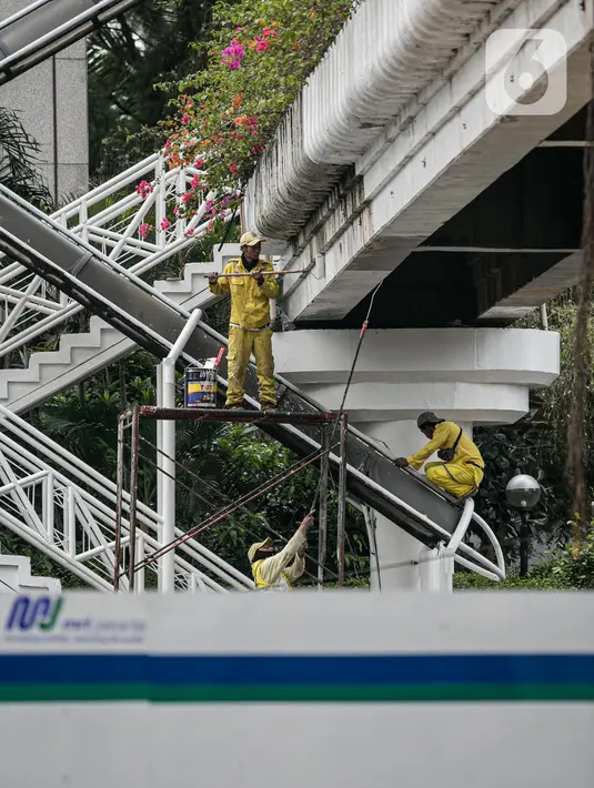 Pekerja Dinas Bina Marga DKI melakukan pengecatan ulang di sejumlah bagian dari Jembatan Penyeberangan Orang (JPO) di kawasan Thamrin, Jakarta, Kamis (28/1/2021). Pengecatan ulang itu sebagai bagian dari perawatan JPO di Jakarta guna memberikan kesan bersih dan indah. (Liputan6.com/Faizal Fanani)