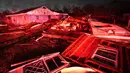 Rumah-rumah yang hancur diterangi lampu mobil pemadam kebakaran setelah tornado melanda daerah di Arabi, La., Selasa (22/3/2022). Tornado menerjang bagian New Orleans dan sekitarnya Selasa malam, menghancurkan kabel listrik dan menyebarkan puing-puing di bagian kota. (AP Photo/Gerald Herbert)