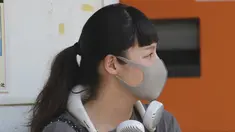 Seorang wanita mengenakan masker wajah untuk membantu melindungi dari penyebaran coronavirus menggunakan kipas angin portabel di lehernya untuk melindungi tubuh dari panas di Tokyo, Rabu, (5/8/2020). (AP Photo/Koji Sasahara)