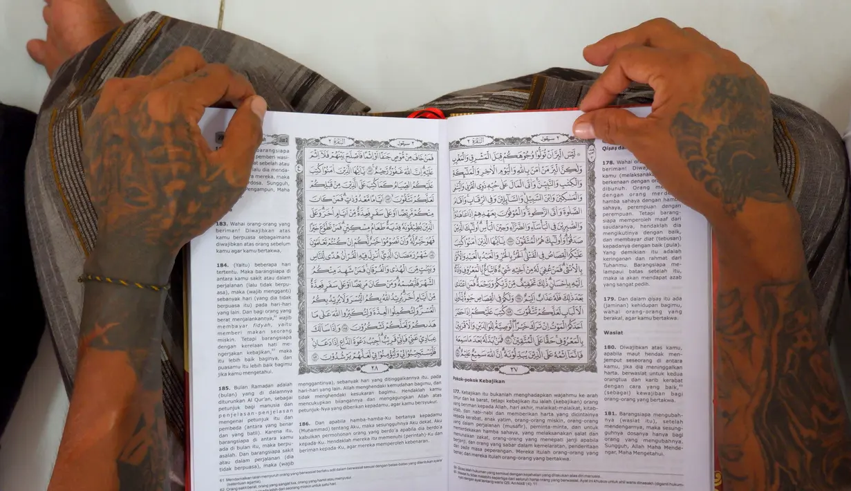 Tangan seorang napi terlihat saat membacakan mushaf Al Quran di sebuah penjara di Serang, Jawa Barat pada 27 Maret 2023. (AFP/Dziki Oktomauliyadi)