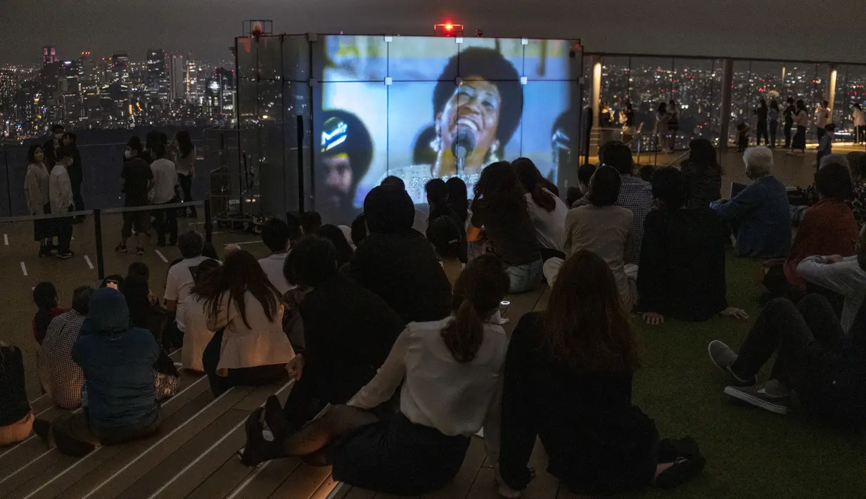 Pengunjung menonton film di rooftop dek observasi Shibuya Sky di Tokyo, Sabtu (9/10/2021). seminggu setelah Jepang sepenuhnya keluar dari keadaan darurat virus corona untuk pertama kalinya dalam lebih dari enam bulan. (AP Photo / Kiichiro Sato)