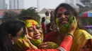 Pra wanita saling mewarnai wajah temannya dengan tepung berwarna-warni untuk merayakan Festival Holi di Kolkata, India, Kamis (1/3). Festival ini juga mendatangi datangnya musim semi. (Dibyangshu SARKAR/AFP)