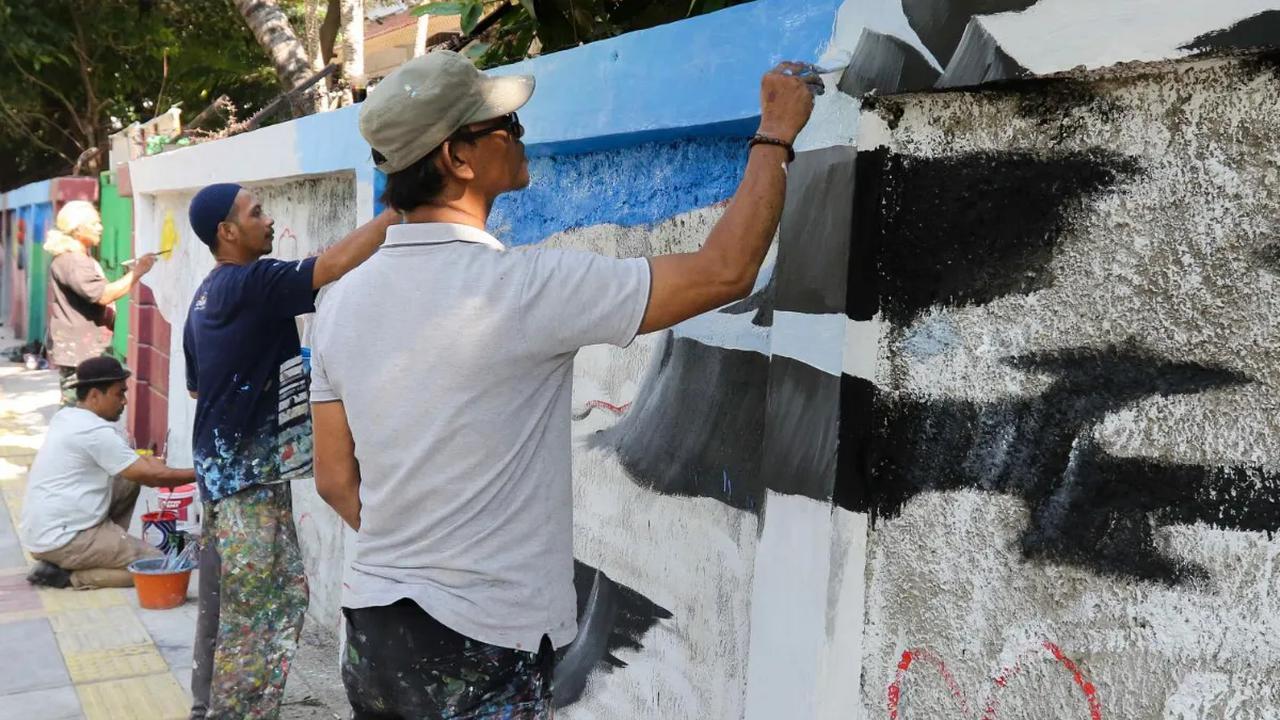 Sejumlah seniman menuangkan ide-ide kreativitasnya pada dinding di pinggir sebuah trotoar jalan di kawasan Cideng, Jakarta, Rabu (29/11/2023). <br>