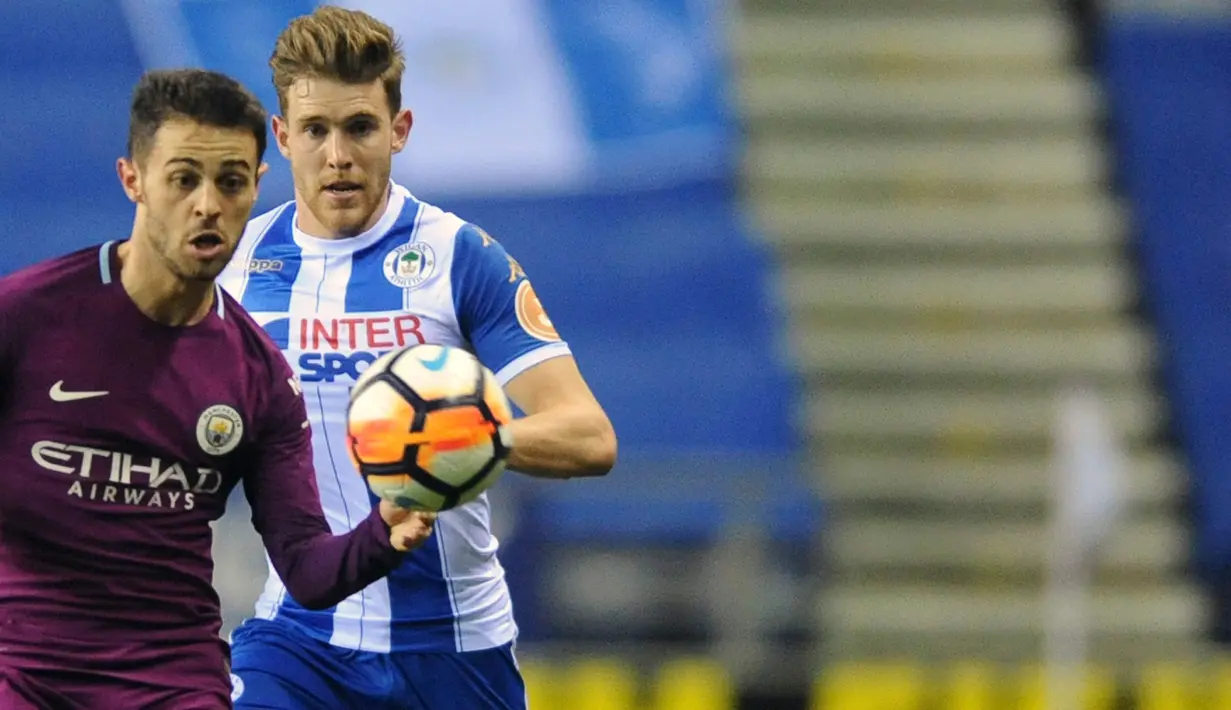 Pemain Manchester City, Bernardo Silva berebut bola bola dengan pemain Wigan Athletic, Callum Elder pada babak kelima Piala FA di DW Stadium, Senin (19/2). Manchester City disingkirkan oleh tim divisi tiga, Wigan, dari Piala FA. (AP/Rui Vieira)