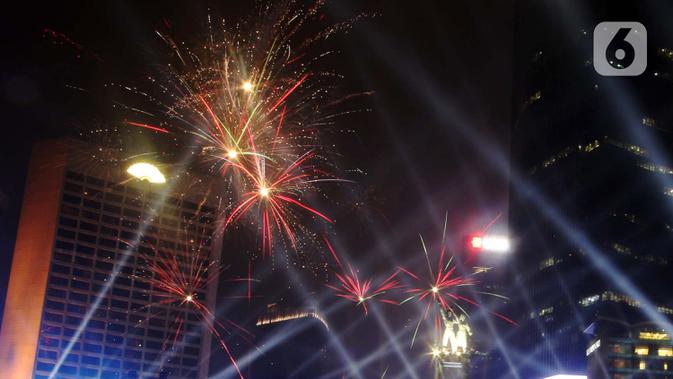 Nyala kembang api memeriahkan suasana malam pergantian tahun di kawasan Bundaran Hotel Indonesia, Jakarta, Selasa (31/12/2019). Ribuan masyarakat melewati malam pergantian tahun 2019 menuju 2020 dengan menyalakan kembang api dan menikmati panggung hiburan. (Liputan6.com/Angga Yuniar)