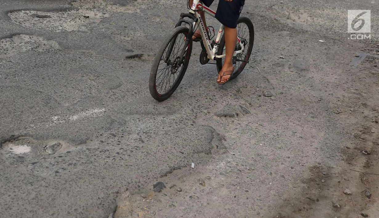 Pengendara sepeda menghindari jalan berlubang di kawasan Gas Alam, Depok, Jawa Barat, Kamis (4/10). Hingga kini kondisi jalan rusak di kawasan tersebut tidak diperbaiki oleh pihak terkait. (Liputan6.com/Immanuel Antonius)