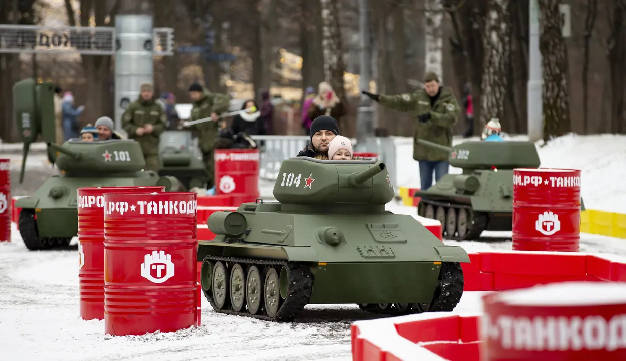 Anak-anak ditemani seorang pria mengendarai model tank T-34 era Soviet yang legendaris di objek wisata petualangan anak-anak Tankodrom di taman Sokolniki di Moskow, Rusia (6/1/2020). Anak-anak dapat berlomba dengan menggunakan tank ini di sekitar kursus slalom. (AP Photo/Alexander Zemlianichenko)