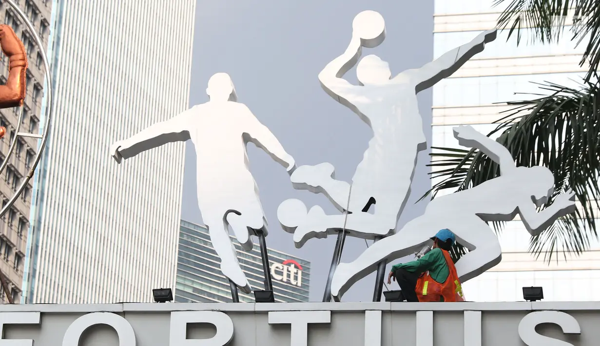 Pekerja membersihkan ornamen di gerbang masuk jalan Pintu Satu Senayan, Jakarta, Jumat (20/7). Jelang perhelatan Asian Games 2018, sejumlah fasilitas penunjang di kawasan Gelora Bung Karno terus dipercantik. (Liputan6.com/Helmi Fithriansyah)