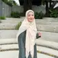 Ciptakan tampilan yang elegan dengan padu padan tiered dress warna gelap dan hijab warna cream cerah. [Foto: IG/natasharizkynew].