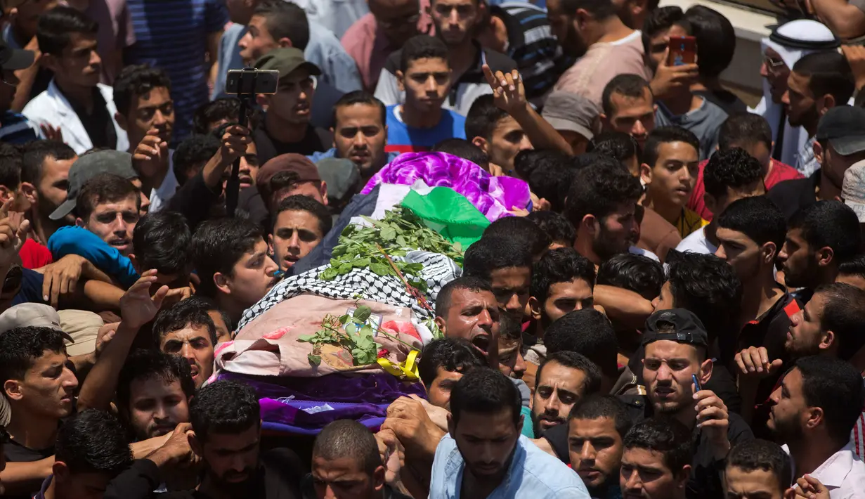 Ribuan pelayat membawa jasad perawat Palestina, Razan Najjar saat pemakamannya di Kota Khan Younis, Jalur Gaza Selatan, Sabtu (2/6). Gadis 21 tahun tersebut terbunuh oleh tembakan Israel pada Jumat, 1 Juni 2018. (AP Photo/Khalil Hamra)