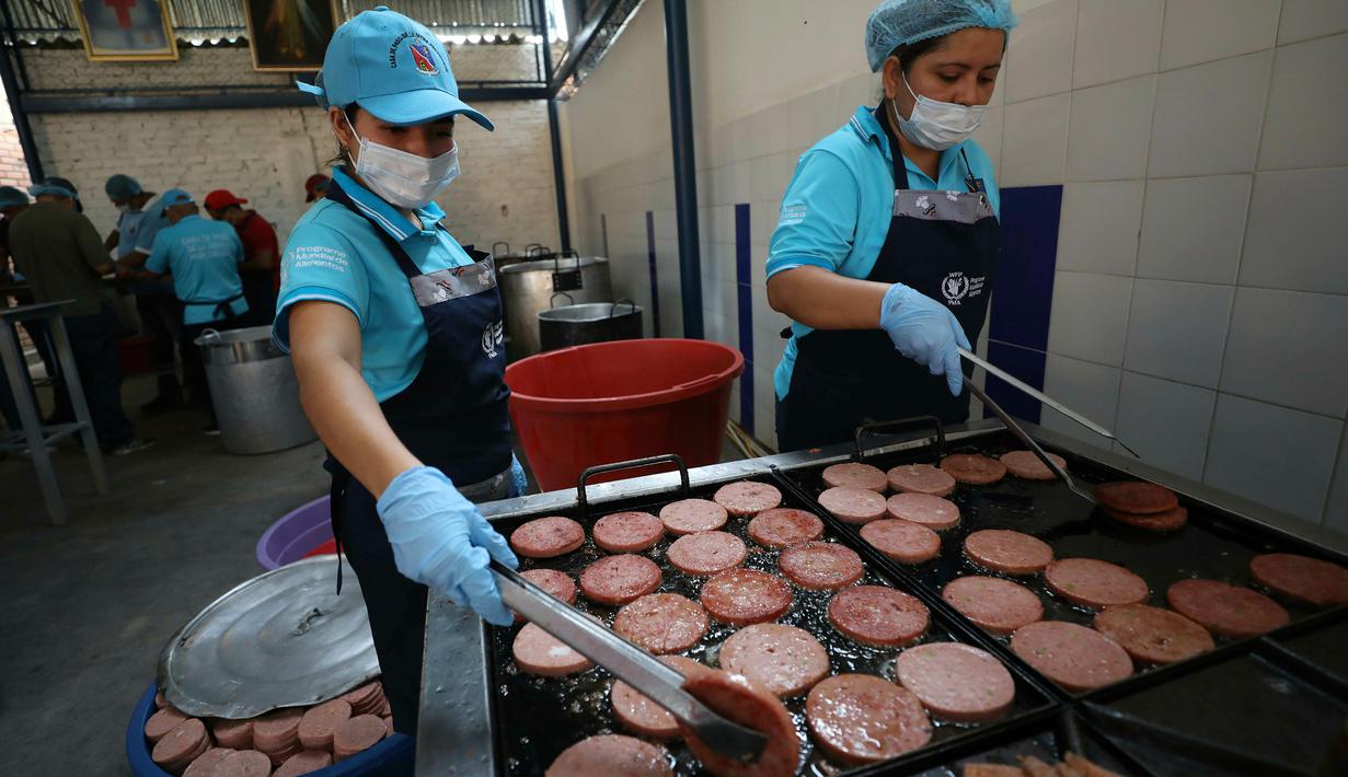 Relawan menggoreng daging bologna untuk pengungsi Venezuela di tempat penampungan Divina Providencia, La Parada, Cucuta, Kolombia, Senin (18/2). Sebagian besar makanan disiapkan untuk imigran Venezuela. (AP Photo/Fernando Vergara)