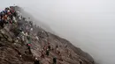 Sejumlah orang mencoba menangkap sajen yang dilemparkan ke kawah dalam ritual Yadnya Kasada di Gunung Bromo, Probolinggo, Jawa Timur, Kamis (18/7/2019). Ritual yang selalu berlangsung pada saat bulan purnama ini sudah dilangsungkan sejak abad ke-14. (JUNI KRISWANTO/AFP)