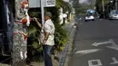 Gonzalo Sanchez melukis pohon mangga yang diberi nama "The Woman in Red Bikini", di sudut jalan di lingkungan Escazu, Kosta Rika, Selasa (1/3). Lukisan tersebut menirukan sosok seorang wanita yang mengenakan bikini. (REUTERS/Juan Carlos Ulate)