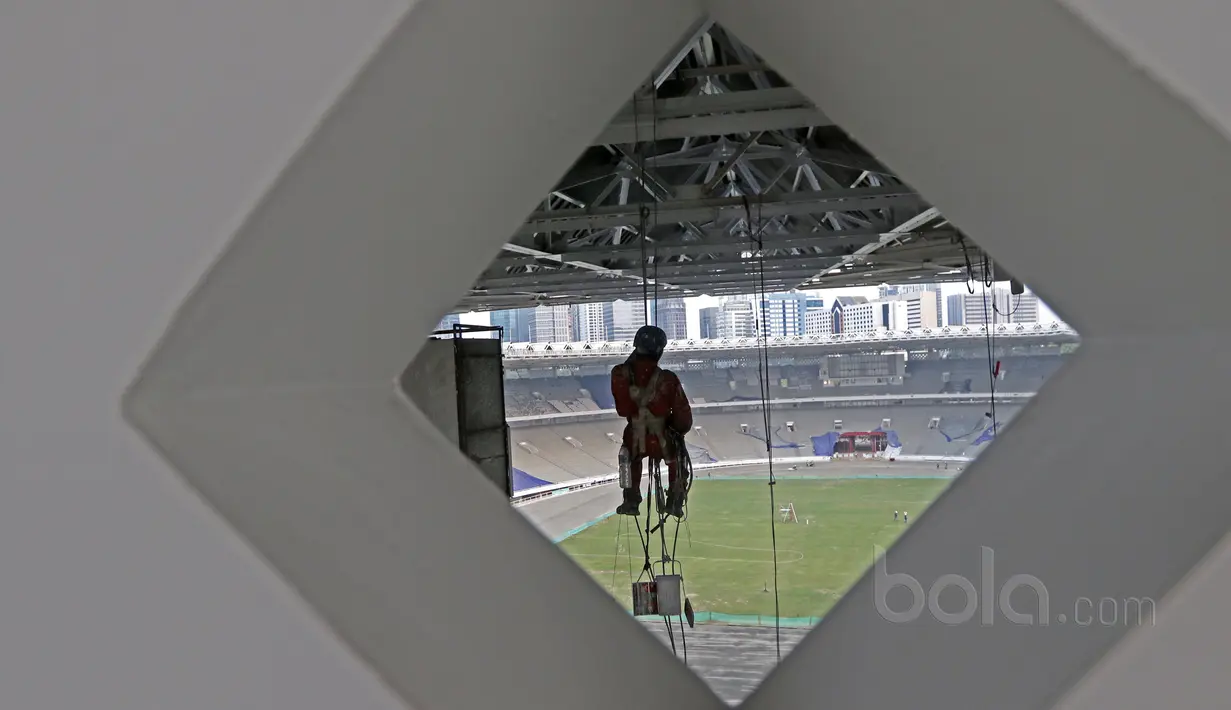Seorang pekerja menggunakan perlengkapan panjat dinding untuk mengecat rangka besi Stadion Utama Gelora Bung Karno di Senayan, Jakarta, Selasa (23/5/2017).  (Bola.com/Nicklas Hanoatubun)