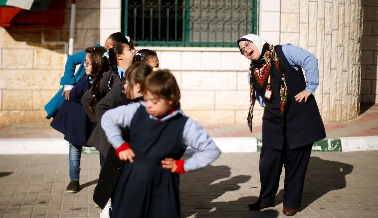 Seorang guru yang menderita Down Syndrome yang bernama Hiba Al-Sharfa ikut berolahraga bersama muridnya di sekolah Asosiasi Hak Hidup di Kota Gaza (21/12). (Reuters/Suhaib Salem)