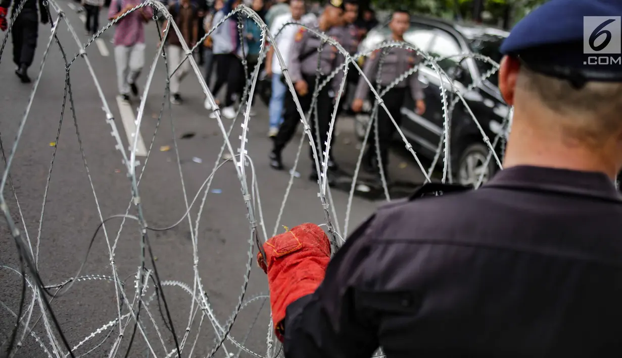 Personel Brimob memasang kawat berduri di sekitar area gedung KPU, Jakarta, Jumat (1/3). Kawat berduri itu untuk mengantisipasi massa Forum Umat Islam (FUI) dan Gerakan Jaga Indonesia yang akan menggelar aksi di depan KPU. (Liputan6.com/Faizal Fanani)