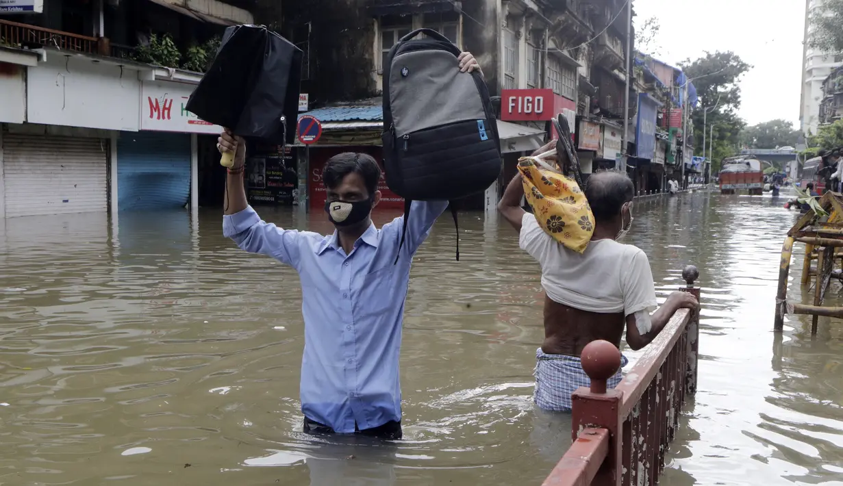 Orang-orang berjalan melewati jalan yang tergenang air setelah hujan lebat di Mumbai, India, Rabu (23/9/2020). Musim hujan di India berlangsung dari Juni hingga September. (AP Photo/Rajanish Kakade)