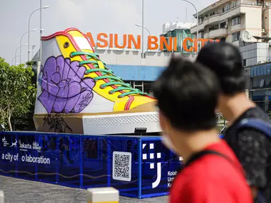 Pejalan kaki melintas di depan Tugu Sepatu, Sudirman, Jakarta, Minggu (19/9/2021). Tugu Sepatu menjadi sasaran pencoretan dengan semprotan aerosol oleh orang tak dikenal sehari usai diresmikan pada 17 September 2021. (Liputan6.com/Faizal Fanani)